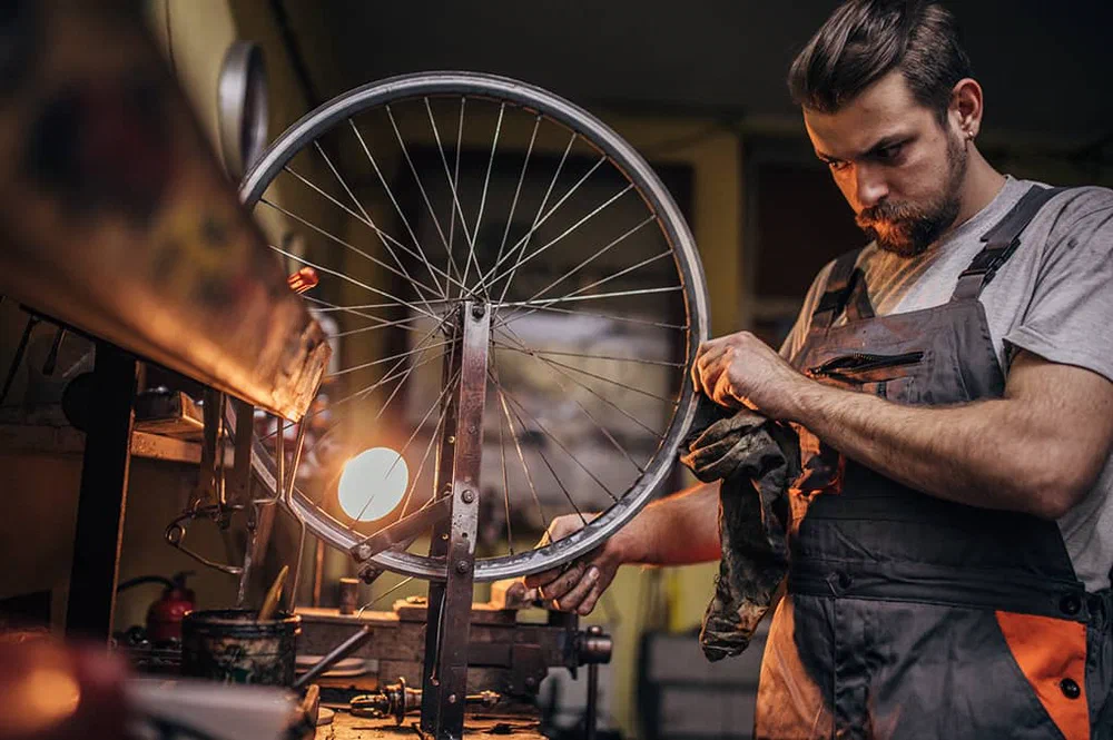 A mechanic truing a bicycle wheel in a workshop